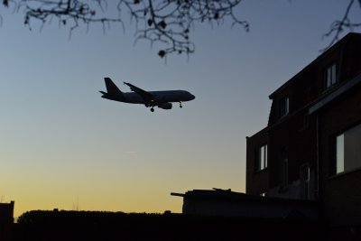 Vliegtuig dat bij valavond boven een woonwijk vliegt